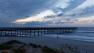 A woman walks on the beach near a pier slightly damaged after Hurricane Earl brushed the North Carolina coast in Atlantic Beach, N.C., Friday, Sept. 3, 2010.