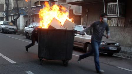 Iranian protestors moving a garbage can which is set on fire, during an anti-government protest in Tehran, Iran.