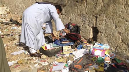 An Egyptian looks through books and school bags that were strewn along the tracks at the scene where a speeding train crashed into a bus carrying children to their kindergarten, killing at least 47