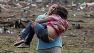 A woman carries a child through a field near the collapsed Plaza Towers Elementary School in Moore, Okla., Monday, May 20, 2013