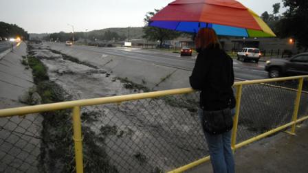 Kelsey McKiel watches as Camp Creek, normally a small stream, races with soot and mud down 31st Street after a flash flood from the Waldo Canyon Fire burn scar swept through Manitou Springs, Colo. on Friday, Aug. 9, 2013