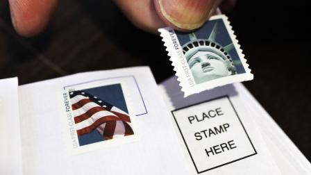 FILE - In this Dec. 5, 2011, photo, a customer places first class stamps on envelopes at a U.S. Post Office in San Jose, Calif. Itll cost another penny to mail a letter in 2013