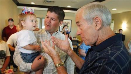 Republican presidential candidate, Rep. Ron Paul, R-Texas, reaches out towards Caroline, 1, daughter of his campaign manager Jesse Benton, center, before he spoke at a campaign event at a hotel in Ames, Iowa, Thursday, Aug. 11, 2011.