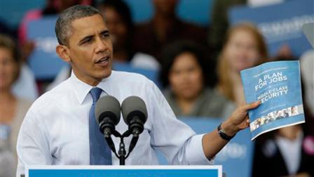 President Barack Obama holds up a copy of his jobs plans while speaking to supporters during a campaign stop at The Mississippi Valley Fairgrounds, Wednesday, Oct. 24, 2012, in Davenport, Iowa.