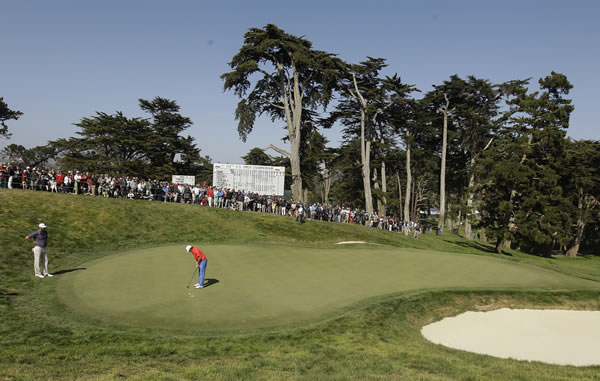 Dustin Johnson watches as Rickie Fowler putts on...