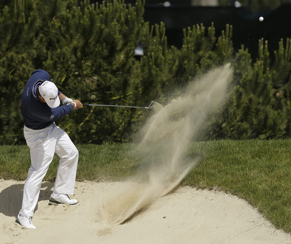 Lee Westwood, of England, hits out of a bunker...