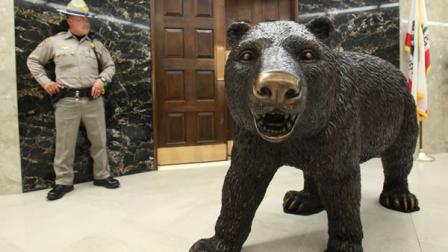 California Highway Patrol office Shawn Bien stands outside the Governors office next to a statue of an 800-pound bronze grizzly bear at the Capitol in Sacramento, Calif., Tuesday, April 7, 2009.