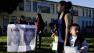 Nine-year-old Ashley Villatoro, left, holds a poster showing an image of former teacher Martin B. Springer as students arrive at Miramonte Elementary School in Los Angeles, Thursday, Feb. 9, 2012.