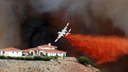 A firefighting air tanker drops fire retardant on a hillside as a wildfire rages, Wednesday Aug. 1, 2012 in Murrieta, Calif.