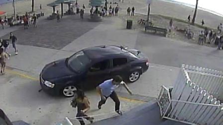 Pedestrians scatter as a car drives through a packed afternoon crowd along the Venice Beach.