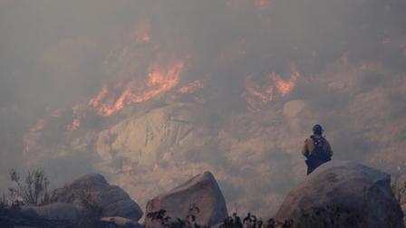 A firefighter watches a backfire burn while battling a wildfire, Thursday, Aug. 8, 2013, in Banning, Calif.