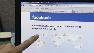 A man points to the Facebook login screen.