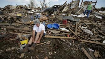 Rick Brown puts on a pair of boots after finding them in his tornado-ravaged home Wednesday, May 22, 2013, in Moore, Oklahoma