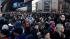 Commuters wait in a line to board buses into...
