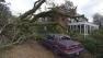 A large tree toppled by a Christmas Day tornado rests on an apartment building as residents clean up and assess the damage Wednesday, Dec. 26, 2012 in Mobile, Ala.