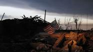 At sunrise Tuesday May 21, 2013, an American flag blows in the wind atop the rubble of a destroyed home in Moore, Okla.