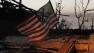At sunrise Tuesday May 21, 2013, an American flag blows in the wind atop the rubble of a destroyed home in Moore, Okla.