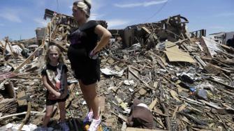 Addison Paul, 7, stands by her mother Leslie as they take a short break from recovery efforts at Pauls tornado damaged home Wednesday, May 22, 2013, in Moore, Oklahoma.