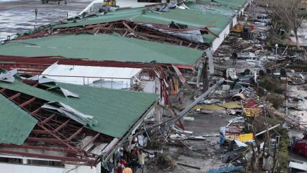 People stay outside the remains of a damaged airport terminal after powerful Typhoon Haiyan slammed into Tacloban city, Leyte province central Philippines on Saturday, Nov. 9, 2013