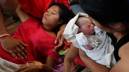 New-born baby Bea Joy is held as mother Emily Ortega, 21, rests after giving birth at an improvised clinic at Tacloban airport Monday Nov. 11, 2013 in Tacloban city, Leyte province in central Philippines.