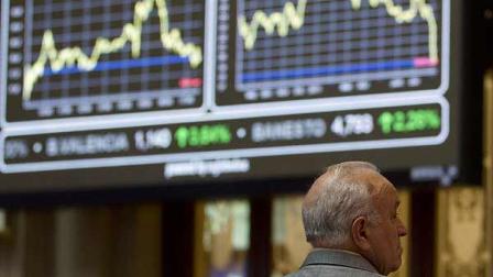A broker looks on in front of the main screen at the Stock Exchange in Madrid Monday Aug. 8, 2011. The borrowing costs of both Spain and Italy dropped sharply in early trading Monday after the European Central Bank signaled it would intervene in the markets to keep the two countries bond prices supported. (AP Photo/Paul White)