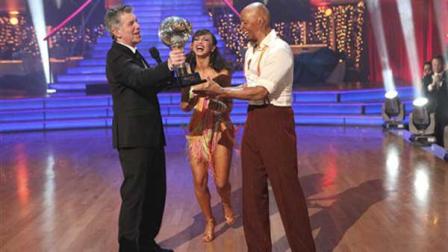 In this image released by ABC-TV, war veteran and actor J.R. Martinez, right, and his partner Karina Smirnoff hold their award with host Tom Bergeron after they were crowned champions of the celebrity dance competition series, Dancing with the Stars, Tuesday, Nov. 22, 2011 in Los Angeles. (AP Photo/ABC-TV, Adam Taylor)