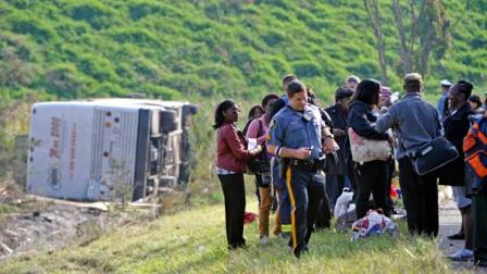 Passengers look on after their bus overturned in a ditch at an exit ramp off Route 80 in Wayne, N.J. Saturday, Oct. 6, 2012. The chartered tour bus from Toronto carrying about 60 people overturned on an interstate exit ramp. Three people have been taken to hospital with non-life-threatening injuries. (AP Photo/Bill Kostroun)