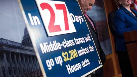 Sen. Charles Schumer, D-N.Y. listens at left, next to a fiscal cliff sign, as Sen. Debbie Stabenow, D-Mich., speaks during a news conference on Capitol Hill in Washington, Wednesday, Dec. 5, 2012, to talk about the debate on tax rates and the fiscal cliff . (AP Photo/ Evan Vucci)