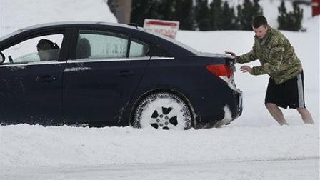 An unidentified man pushes a car through a snow covered intersection in Lawrence, Kan., Thursday, Feb. 21, 2013. Kansas was the epicenter of a winter storm, with parts of the state buried under 14 inches of powdery snow, but winter storm warnings stretched from eastern Colorado through Illinois. (AP Photo/Orlin Wagner)