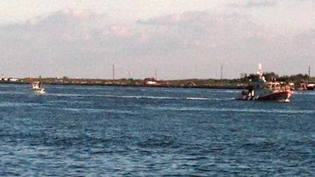 A boat crew aboard a 45-foot Response Boat - Medium, tows a disabled boat and two people to safety