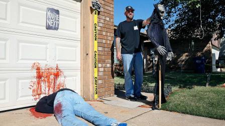 Johnnie Mullins poses with his controversial Halloween display featuring headless dummies dressed in his work clothes at his home