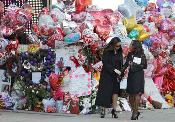 Two women pause near a memorial display before...