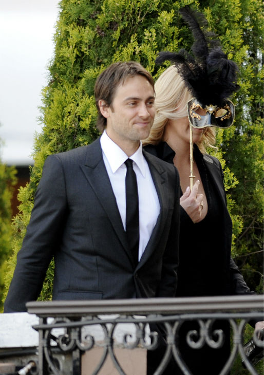 Charlize Theron covers her face with a mask as...