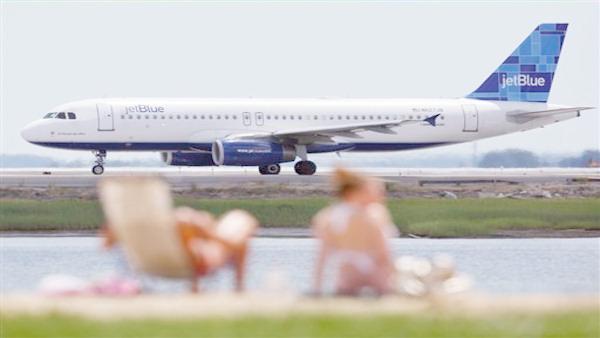 In this July 14, 2009 file photo, a JetBlue plane taxis on the runway in front of sunbathers on Constitution Beach in Boston. (AP Photo/Michael Dwyer, file)