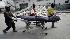 Men pull a stretcher with the body of a woman...
