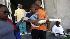 A child with an injured leg is carried outside...