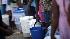 People hold buckets as they wait in line to fill...