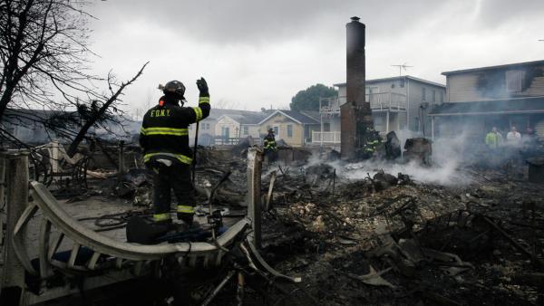 A fire fighter surveys the smoldering ruins of a house in the Breezy Point section of New York, Tuesday, Oct. 30, 2012. More than 50 homes were destroyed in a fire which swept through the oceanfront community during superstorm Sandy.