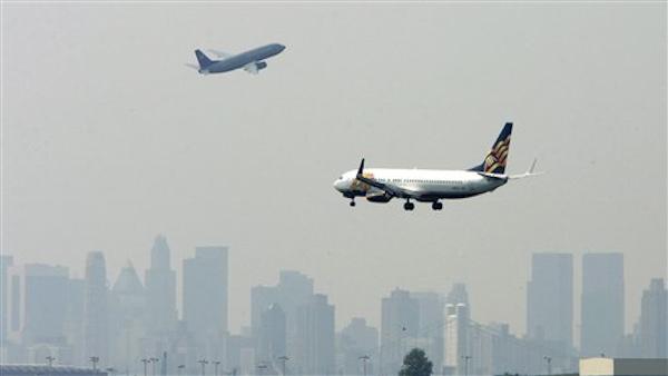 An airplane descends for landing as another takes off at La Guardia Airport. (AP Photo)