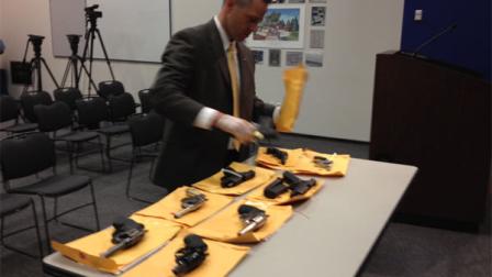 Jason Brown, a Chicago Police Department gang investigations officer, displays 10 guns recovered Wednesday during a joint Chicago Police/DEA sting. (photo by ABC7s Ben Bradley)