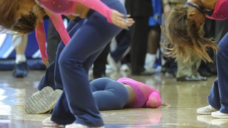 An Atlanta Hawks cheerleader lays on the ground as fellow cheerleaders continue to perform during a dance routine in which hit the floor during the second half of an NBA basketball game against the Dallas Mavericks, Monday, March 18, 2013, in Atlanta. Dallas won 127 to 113. She was taken off the court on a stretcher to a medical facility. (AP Photo/John Amis)