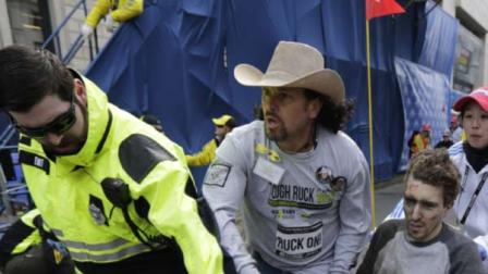 An emergency responder and volunteers, including Carlos Arredondo in the cowboy hat, push Jeff Bauman (lower right) in a wheelchair after he was injured in an explosion near the finish line of the Boston Marathon