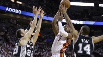 Miami Heat shooting guard Dwyane Wade (3) looks to pass under pressure from San Antonio Spurs point guard Gary Neal (14), Manu Ginobili and center Tiago Splitter (22) of Brazil during the first half of Game 6 of the NBA Finals basketball game.