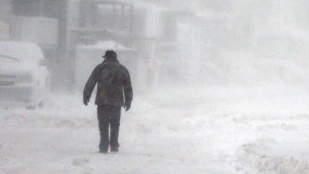 A man walks in the snow down a road along the shore in Scituate, Mass., Friday, Jan. 3, 2014.