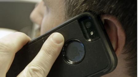 A man poses holding his cell phone Monday, Jan. 13, 2014, in Minneapolis. Lawmakers in the Minnesota House face a pre-filing deadline for bills ahead of the 2014 legislative session. A lawmaker is seeking a bill to require that providers include a kill switch to remotely disable lost or stolen phones.