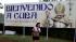 A woman walks past a sign welcoming Pope...