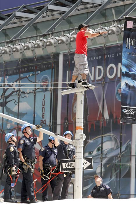 New York City police officers watch while an unidentified man who climbed a traffic light pole in New York's Times Square, Tuesday, June 28, 2011 .  (AP Photo/Mary Altaffer)