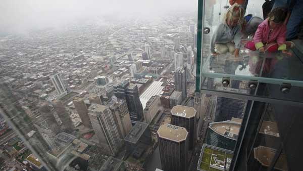 Anna Kane, 5, left, of Alton, Ill., and Sophie Allaway, 4, of Glen Ellen, Ill., wear jackets while looking down at the cool Windy City from The Ledge, at the Sears Towers Skydeck on July 1, 2009. (AP Photo/Kiichiro Sato)