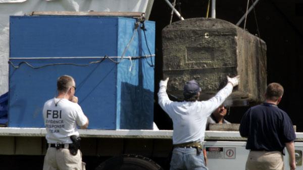 An FBI Evidence Response Team member watches as a vault containing a coffin, believed to hold the remains of Emmett Till, as it is loaded onto a truck at the Burr Oak Cemetery in Alsip, Ill., in this June 1, 2005, file photo. (AP Photo/Charles Rex Arbogast, File)