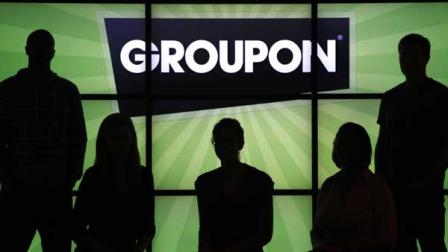 In this Sept. 22, 2011, file photo, employees at Groupon Inc. pose in silhouette with the company logo in the lobby of the online coupon companys Chicago offices.